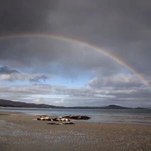 Bay of small Isles on the Isle of Jura, looking north, with rainbow arcing from the mainland on the left over