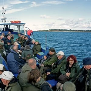 Birdwatchers on boat, with Tresco in distance, Isles of Scilly, England, October