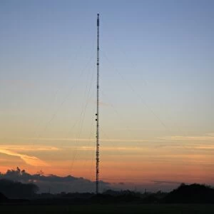 Broadcasting and telecommunication facility with guyed steel lattice mast silhouetted at sunset, Mendlesham Mast, Mendlesham Transmitting Station, Mendlesham, Suffolk, England, november