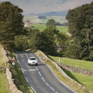 Country road with car passing cyclists, near Hawes, Wensleydale, Yorkshire Dales N. P Country road with car passing cyclists, near Hawes, Wensleydale, Yorkshire Dales N. P