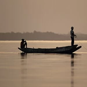 Fishermen in boat on river at sunset, River Gambia, Tendaba, Gambia, february