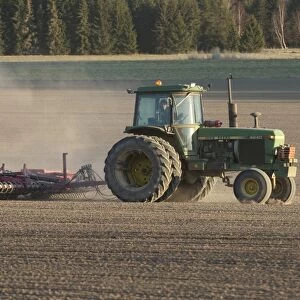 John Deere 4240 tractor with harrows, harrowing field seedbed, Sweden, may