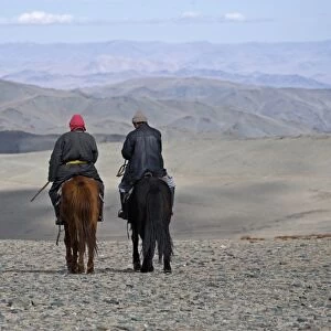 Two Kazakh nomads on horseback with dog, Altai Mountains, Bayan-Ulgii, Western Mongolia, october