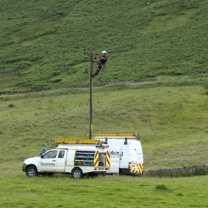 Mains electric technicians repairing cable on rural electricity pole, Cumbria, England, July Mains electric technicians repairing cable on rural electricity pole, Cumbria, England, July