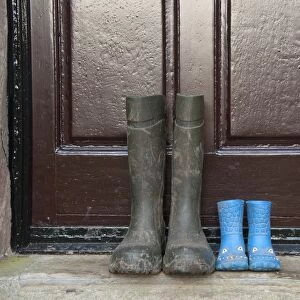 Two pairs of wellington boots, one childrens pair and one mens pair, outside farmhouse door, Whitewell, Lancashire