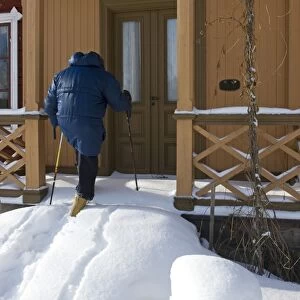 Person walking up snow covered steps to house door, Sweden, february