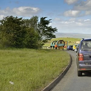 Queue of traffic behind horse drawn Gypsy caravans on road to Appleby Fair, Cumbria, England, may