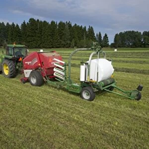 Silage crop, John Deere 4455 tractor with round baler and bale-wrapper, baling and wrapping round bales, Sweden, august