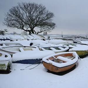 Snow covered boats moored at edge of mudflats, Holbrook Creek, River Stour, Stour Estuary, Lower Holbrook