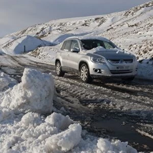 Snow and slush covered road with car on moorland, Yorkshire Dales N. P. North Yorkshire, England, January