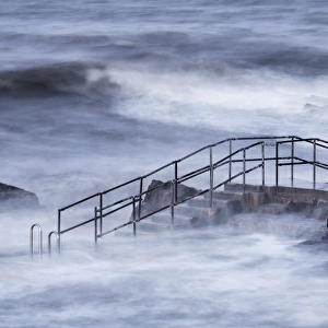 Steps of tidal swimming pool above breaking waves during incoming tide on windy morning, Bude Sea Pool, Summerleaze