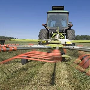 Tractor with Cls Liner 350 rotary rake, turning cut grass for silage crop, Sweden