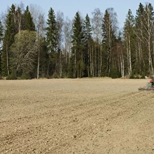 Tractor pulling harrows, harrowing field, Sweden, spring