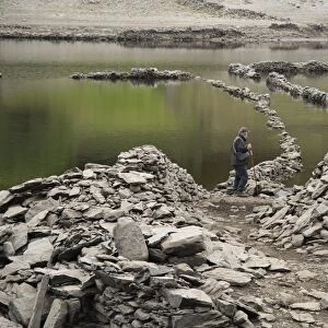 Upland reservoir with low water level and remains of submerged village exposed after dry summer, Mardale Green
