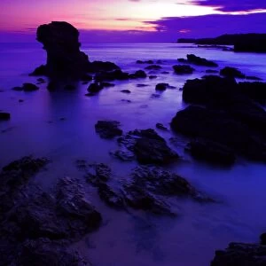 View of beach with rocks silhouetted at sunset, Porth Dafarch, Anglesey, Wales, September