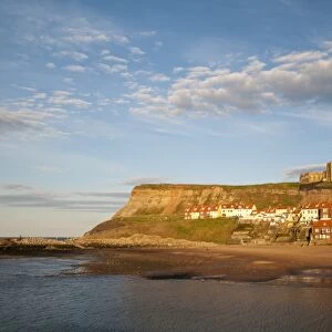 View of beach and seaside town in evening sunlight, with St. Marys Church on clifftop in background, East Cliffs