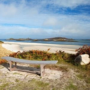 View of bench, sandy beach and coastline, looking towards Foremans Island, Northwethel and Round Island on horizon