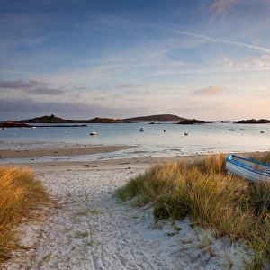 View of boat on beach and moored in bay at sunrise, Porth Green, Old Grimsby, Tresco, Isles of Scilly, England