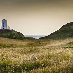 View of lighthouse, cross and coastline on tidal island, Llanddwyn Island, Newborough Warren National Nature Reserve