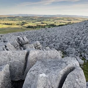 View of limestone pavement at sunrise, Fell End Clouds, looking towards Eden Valley, Cumbria, England, November