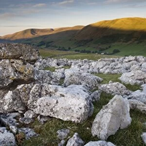 View of limestone pavement at sunrise, Fell End Clouds, looking towards Howgill Fells, Cumbria, England, November