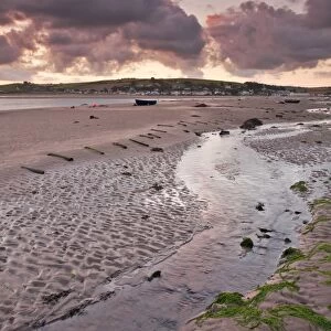 View of rainclouds gathering over sand banks of river estuary at sunrise, village of Instow on opposite bank