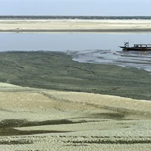 View of riverbank and river with low water levels, with stranded boat, River Brahmaputra, Kaziranga N. P