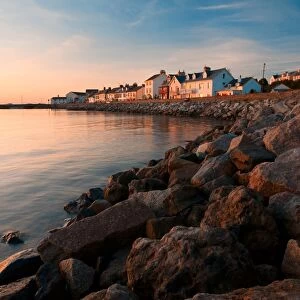 View of sea wall and houses of seaside village overlooking harbour at sunset, Instow, North Devon, England, september