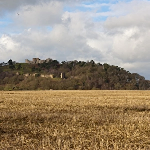 View over stubble field towards castle on sandstone crag, Beeston Castle, Beeston, Cheshire, England, january
