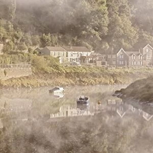 View of village on riverbank in mist at dawn, Tintern, River Wye, Wye Valley, Monmouthshire, Wales, august