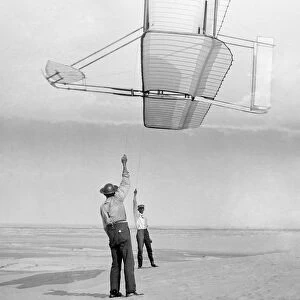 Dan Tate (left) and Wilbur Wright, flying a glider as a kite at Kitty Hawk, North Carolina. Photographed by Orville Wright, 19 September 1902