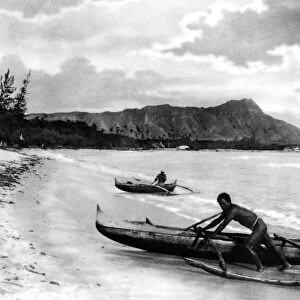 HAWAII: CANOES, c1922. Two natives with outrigger canoes at the shoreline in Honolulu, Hawaii