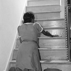 MAID CLEANING, 1941. An African American maid cleaning a staircase in Washington, D