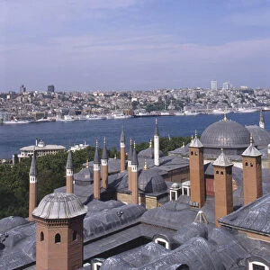 Asia, Turkey, Istanbul, domed rooftops and minarets of the Harem at the Topkapi Palace, Topkapi Sarayi, in foreground, river beyond, modern cityscape on opposite bank in background