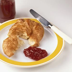 Croissant and jam on a plate together with a knife
