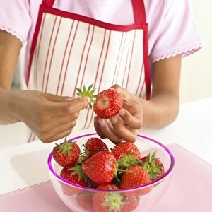 Girl plucking stems from strawberries