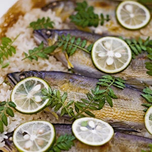Grilled sweetfish (ayu) on bed or rice, with lemon and kinome garnish, close-up