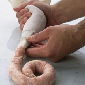 Hands squeezing sausage mixture from piping bag
