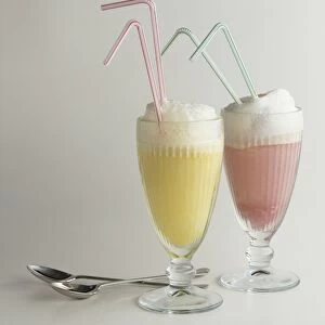Two ice cream sodas in tall glasses with straws