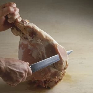 Man carving a cooked ham