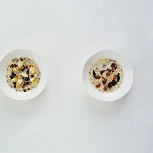 Muesli in white bowls with dried fruit and nuts