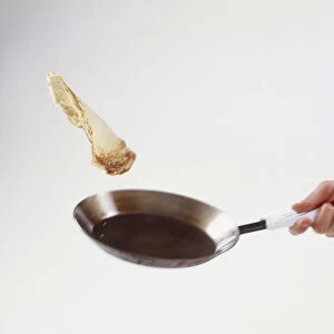 Person holding out pan, tossing crepe in air
