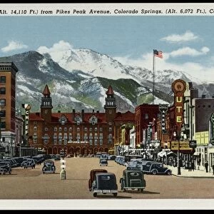 Pikes Peak Avenue. ca. 1937, Colorado Springs, Colorado, USA, 539-Pikes Peak (Alt. 14, 110 Ft. ) from Pikes Peak Avenue, Colorado Springs, (Alt. 6, 072 Ft. ), Colorado. Pikes Peak Avenue is a broad and stately street pointing directly toward the Peak from which it is named that looms above it. At the west it terminates at the Antlers Hotel whose graceful towers form a perfect sight like those on a rifle for the view of Pikes Peak. In the summer season it is thronged with visitors of every station in life from every state and country, for the Avenue is the center of tourist activity. Few who have traversed its broad pavements will forget it as it is one of the most impressive street spectacles in the world