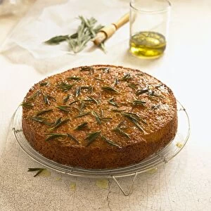 Polenta cake and rosemary, with glass of olive oil, pastry brush and sprigs of rosemary nearby
