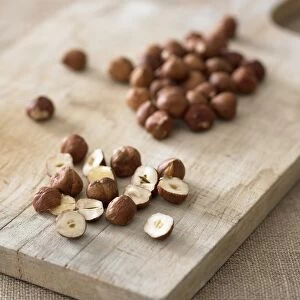 Whole and sliced hazelnuts on chopping board