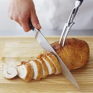 Turkey breast being sliced with knife and carving fork, high angle view