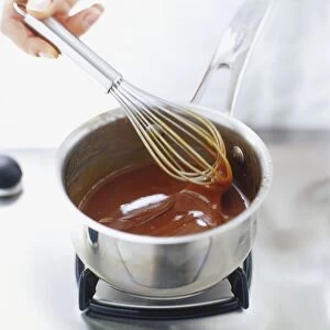 Using a hand whisk to stir caramel sauce