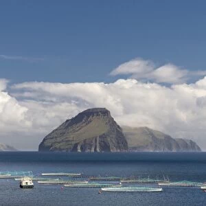Fish farm, clouds and sea, in front of the smallest inhabited island of the Faroe Islands, Koltur, Utoyggjar, Faroe Islands, Denmark