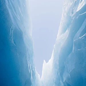 Looking up at the blue sky from deep with in a glaciers jagged crevasse