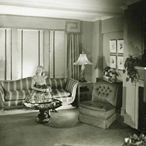 Woman sitting on sofa in stylish living room, (B&W)